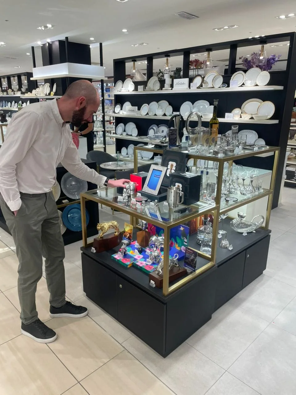 Butikkmedarbeider arrangerer Royal Selangor display med figurer og barware